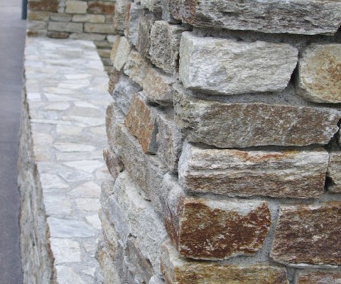 Einfriedung aus Pfeilern mit Naturstein und Trockenmauer
